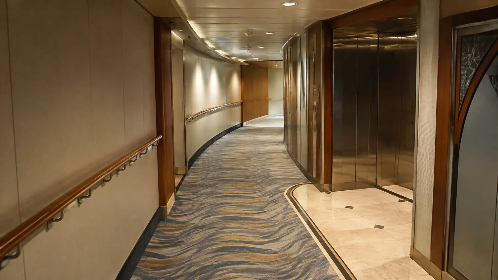 Carpeted corridor curving past a bank of elevators.