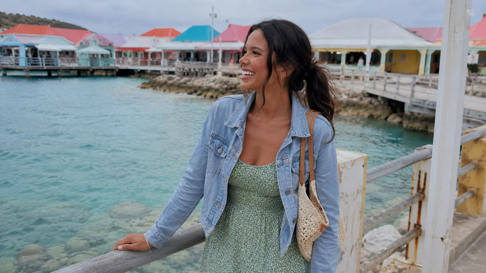 Woman leaning on a railing beside colorful port buildings