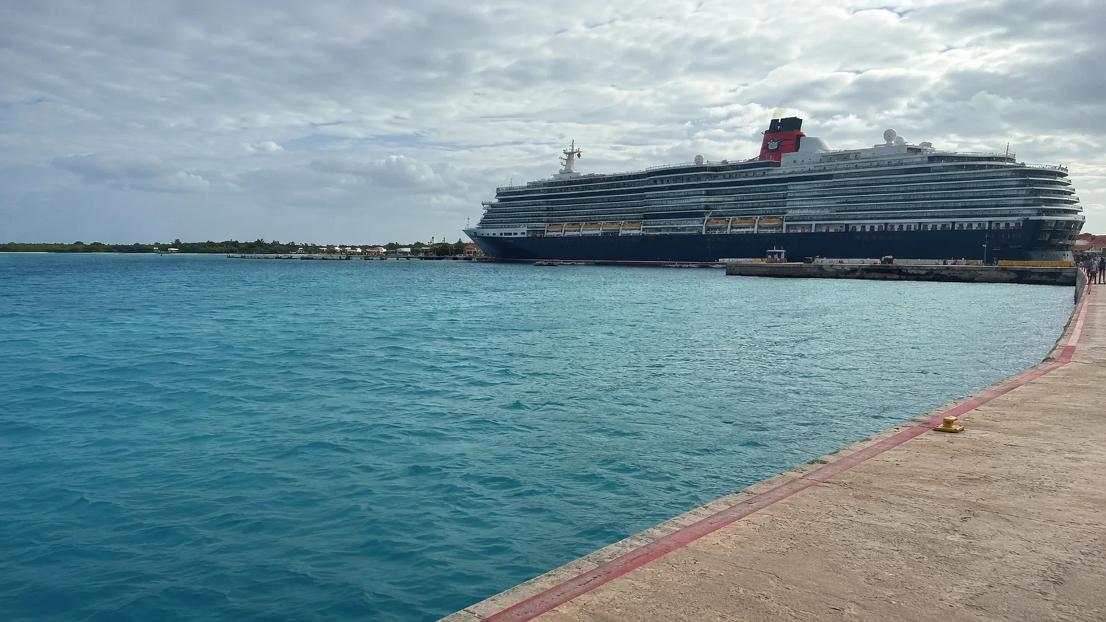 Cruise ship offshore beyond a turquoise harbor