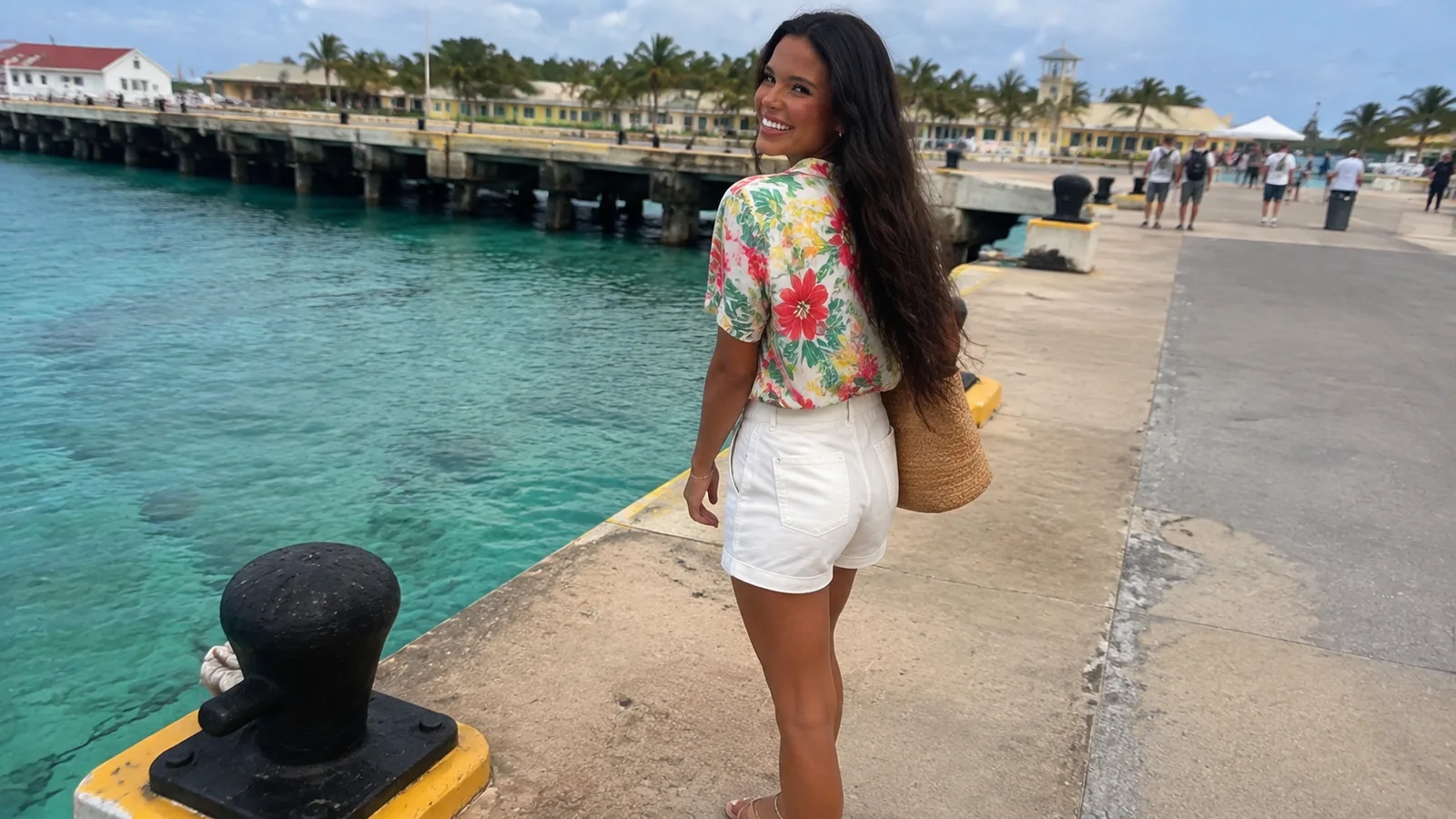 Woman walking on a pier beside turquoise water