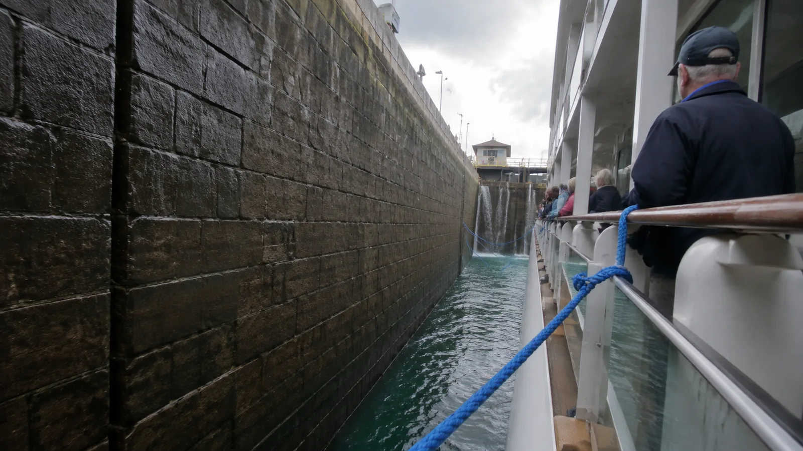 Passenger vessel moving through a narrow stone-sided lock.