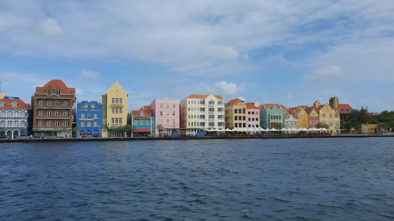 Colorful gabled buildings lining a waterfront beneath a blue sky.