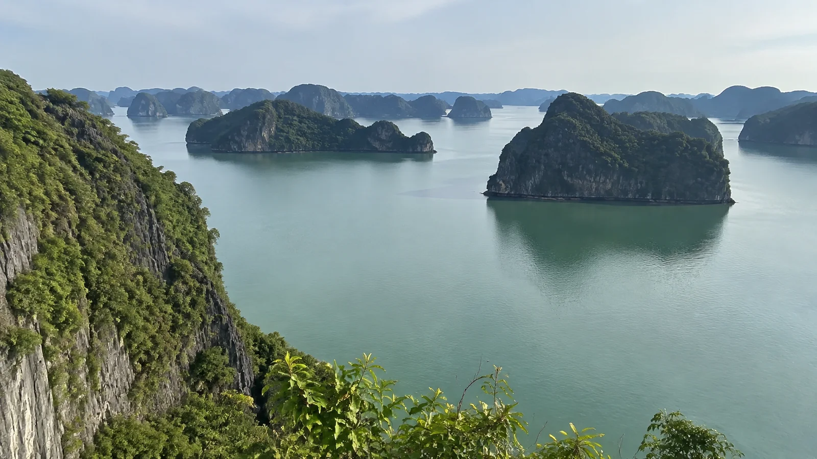 Elevated view across calm water dotted with steep green limestone islands.