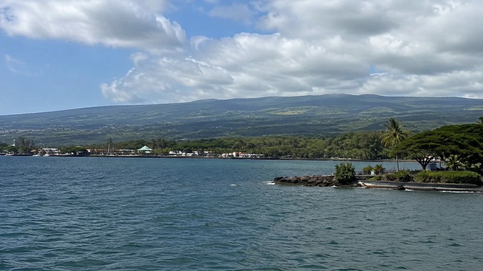 Green volcanic slopes above a coastal settlement and bay