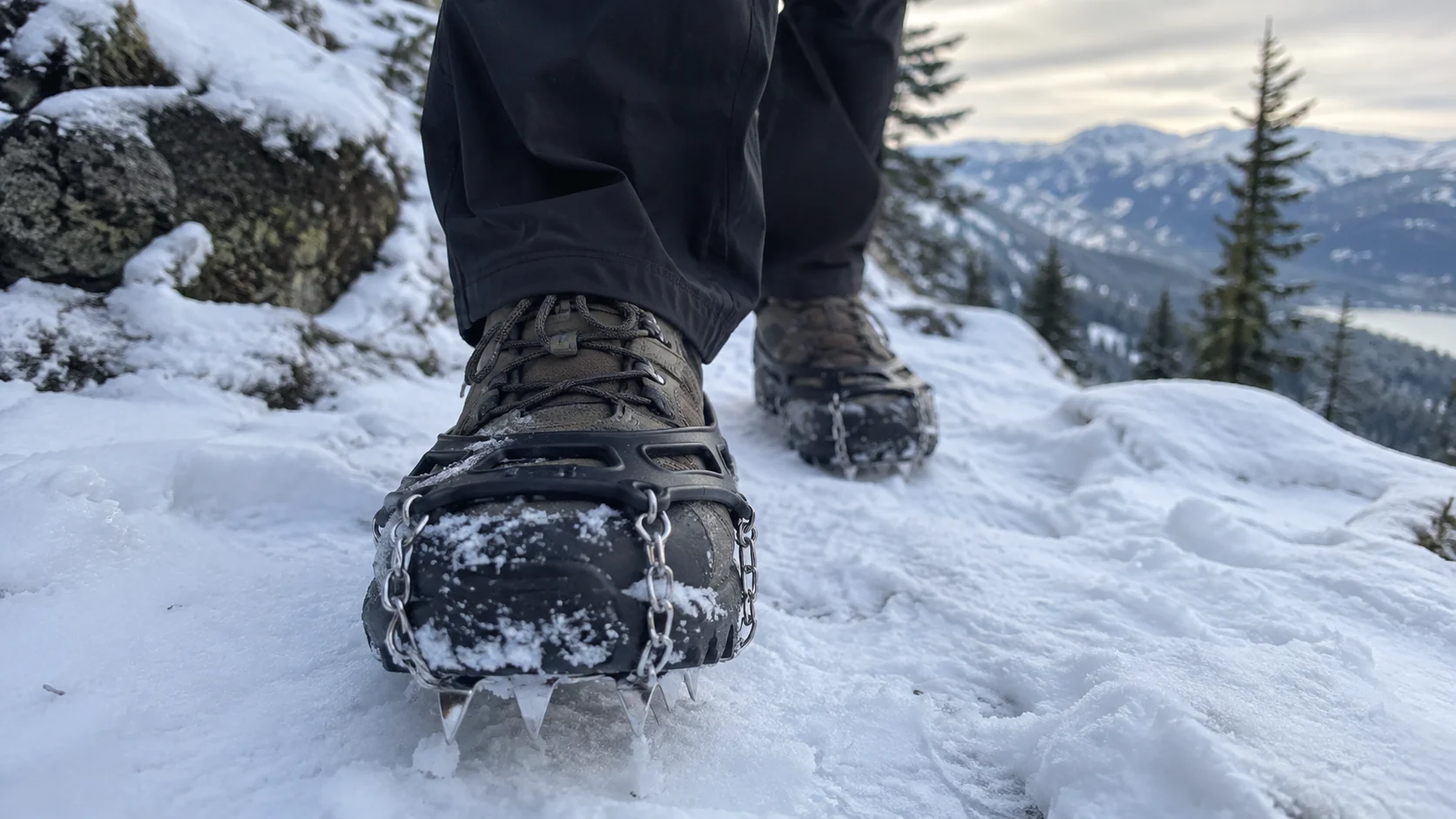 Microspikes fitted to boots on a snowy hiking trail.