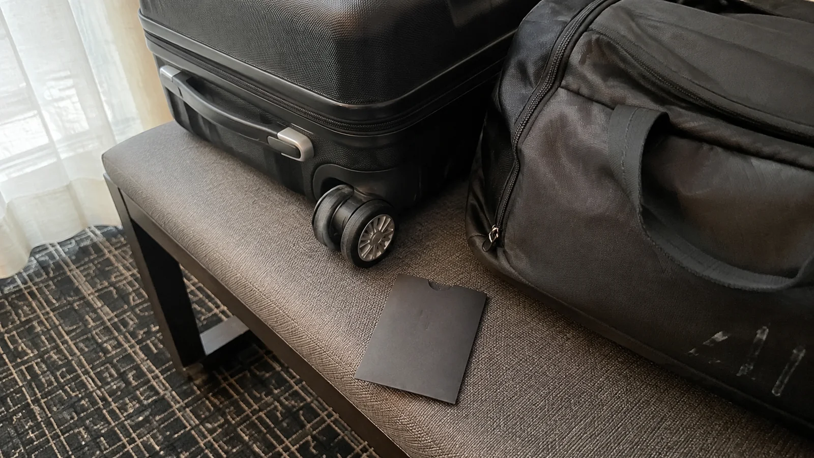 Suitcase and travel bag resting on a hotel room luggage bench