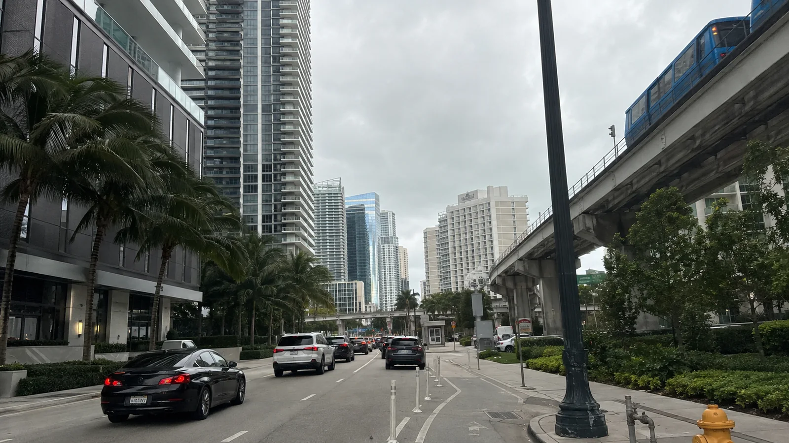 Downtown street lined with high-rise buildings beside an elevated train