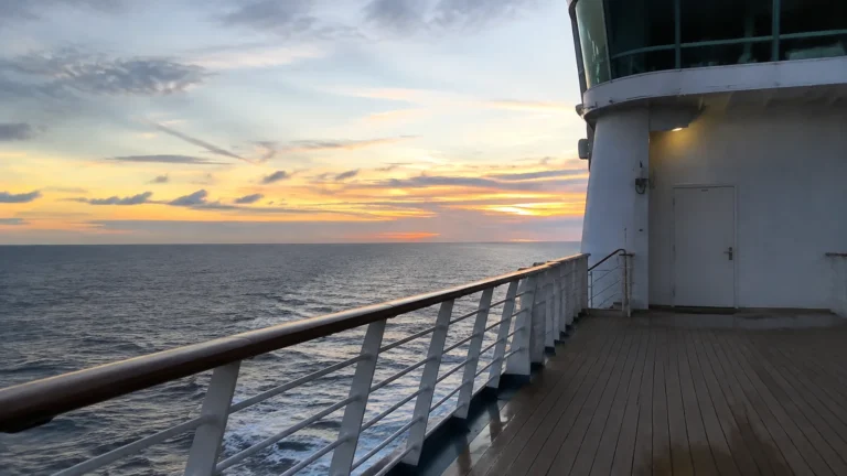 Quiet ship promenade overlooking the ocean at sunset.
