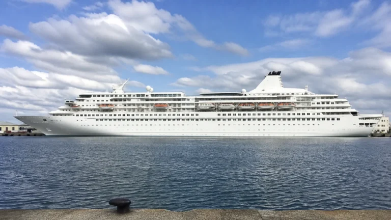 Long white cruise ship viewed broadside across the water.