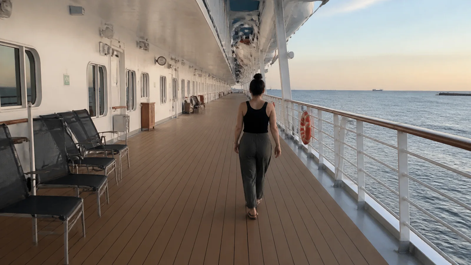 Woman walking along a long covered ship promenade.