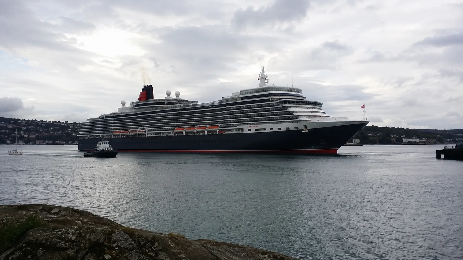Large dark-hulled ocean liner viewed across a harbor.
