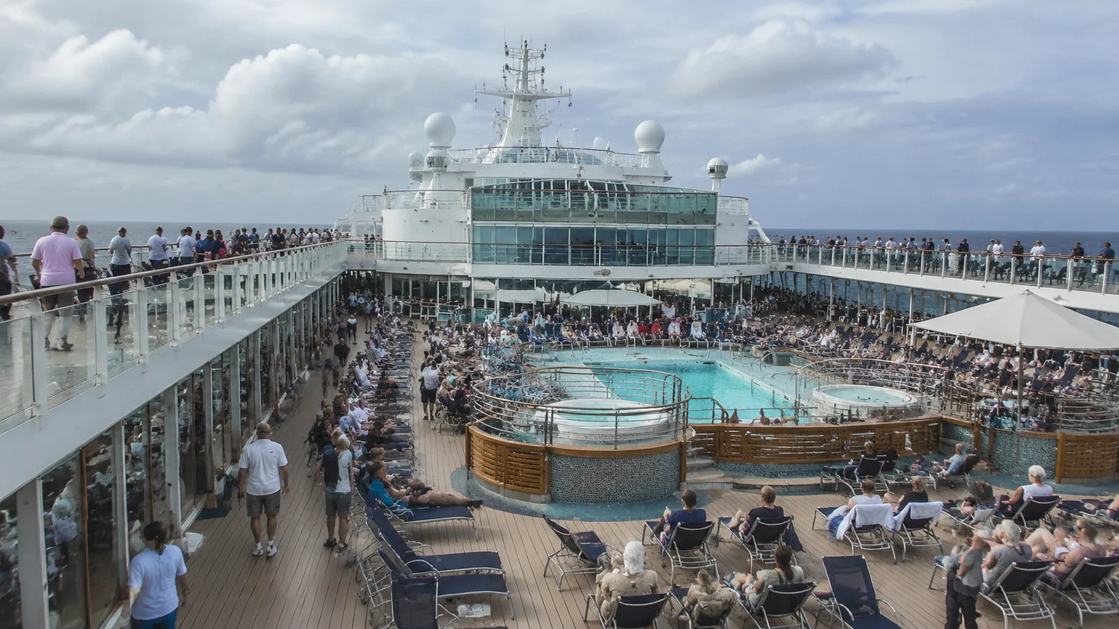 Busy cruise ship pool deck filled with passengers