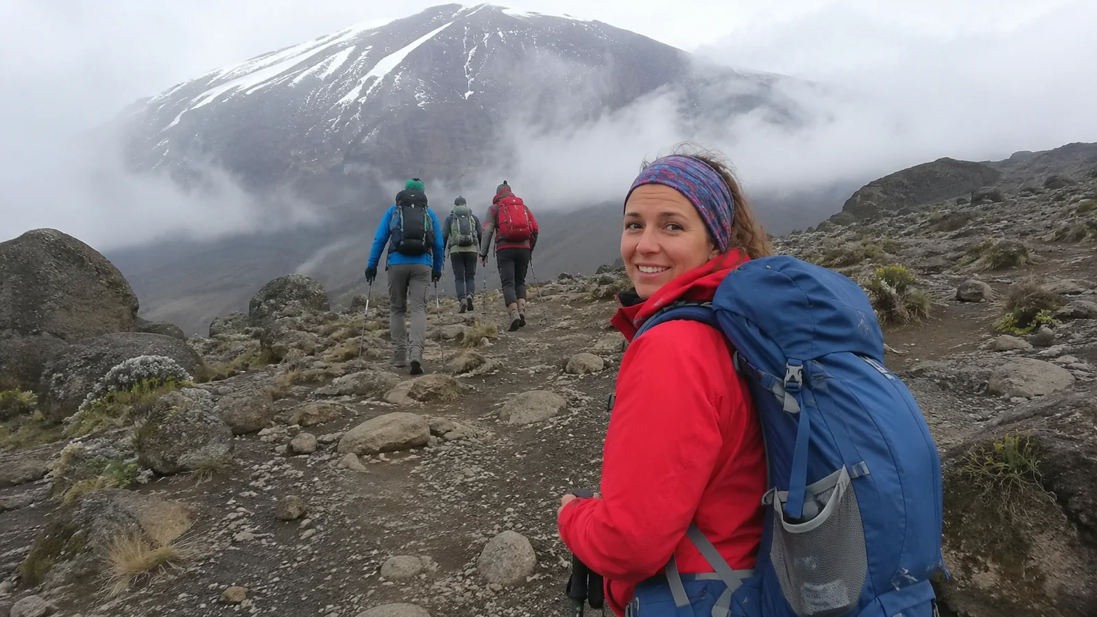 Woman with a large backpack hiking along a rocky mountain trail