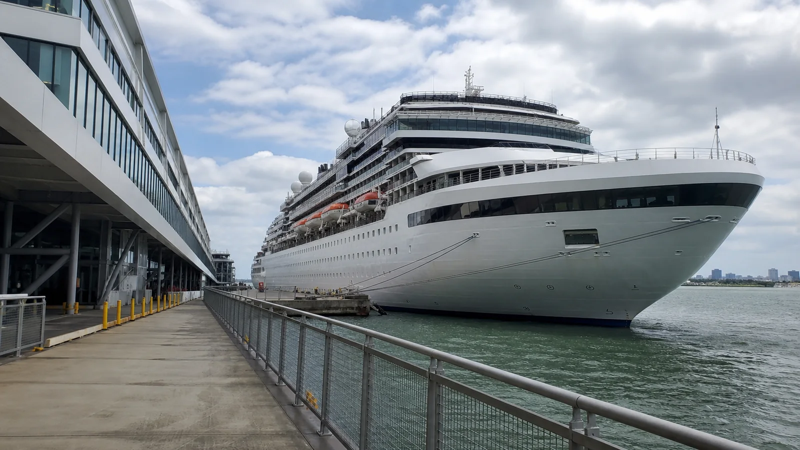 Large cruise ship moored directly beside a terminal building.