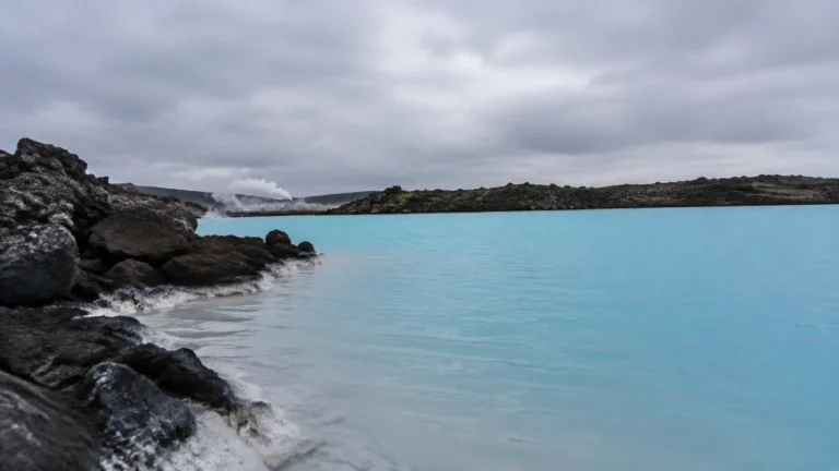 Milky-blue geothermal pool surrounded by dark volcanic rock.