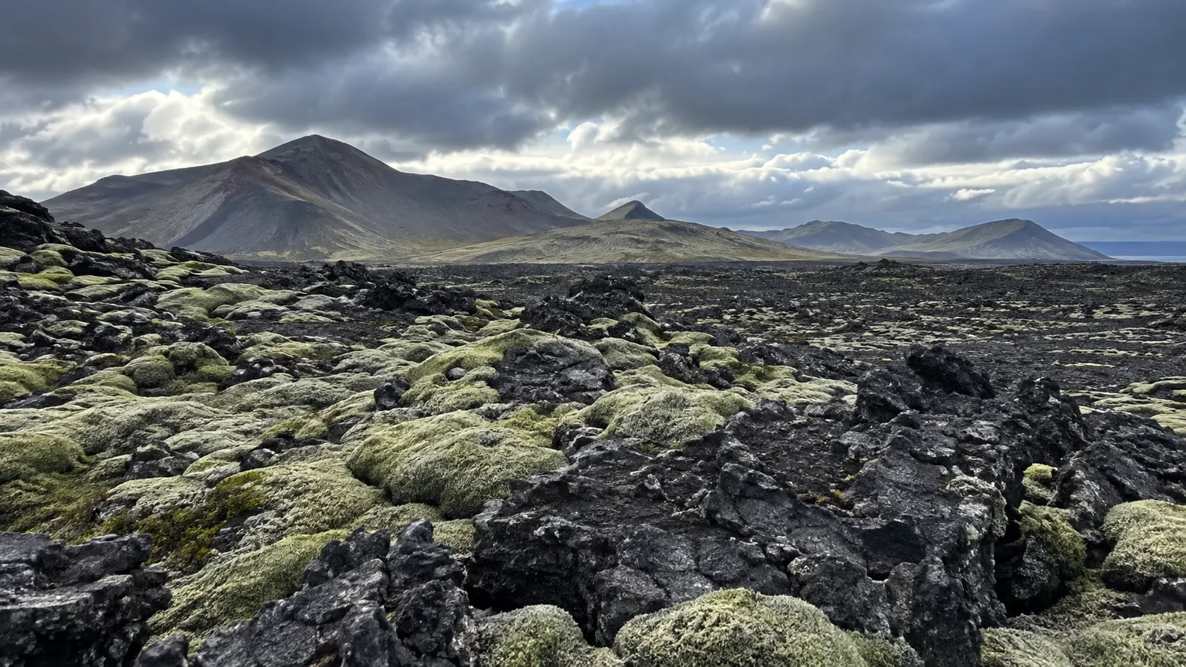 Moss-covered lava field and volcanic ridges on the Reykjanes Peninsula.