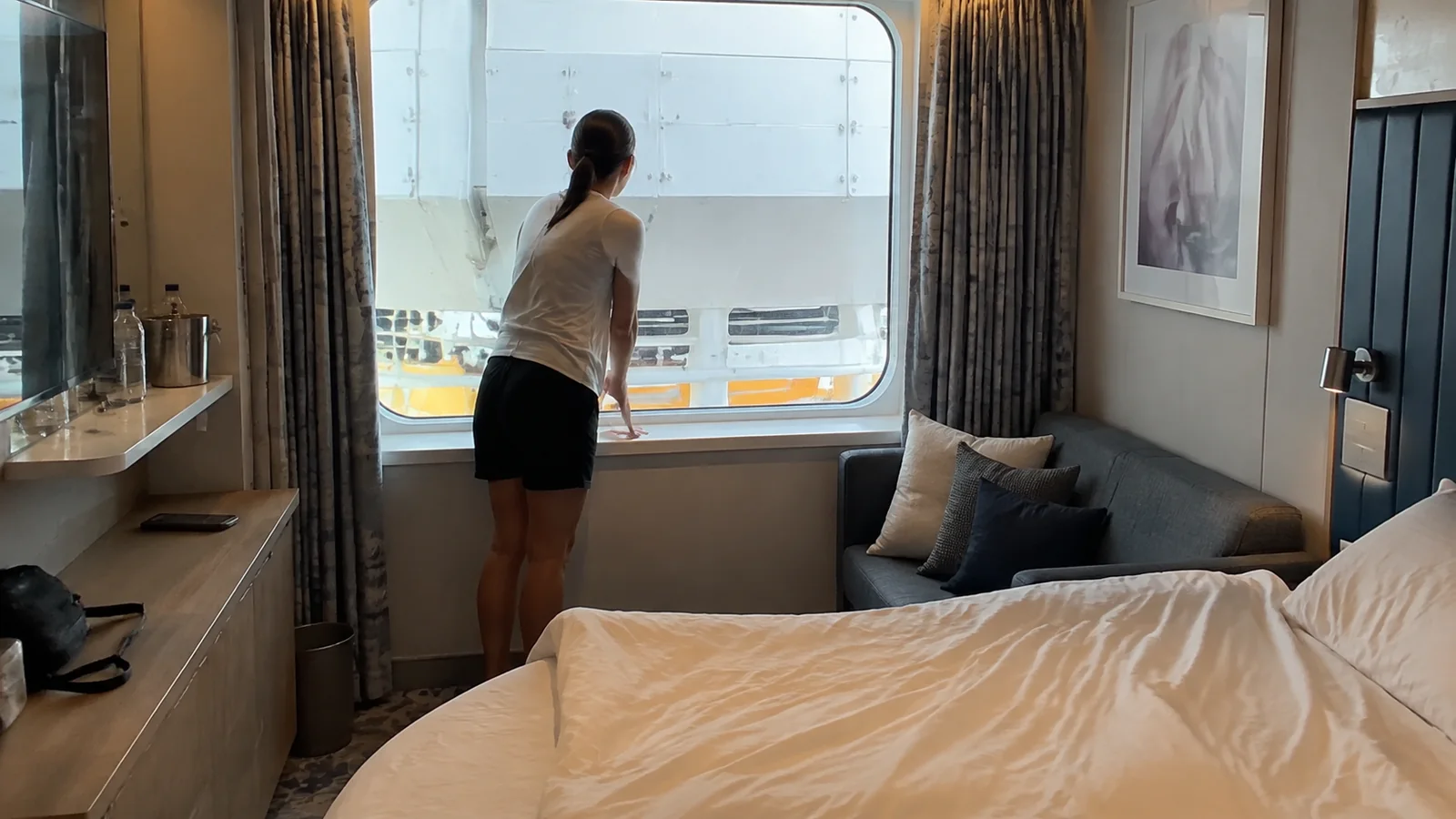 Woman looking through a cruise cabin window blocked by exterior ship equipment