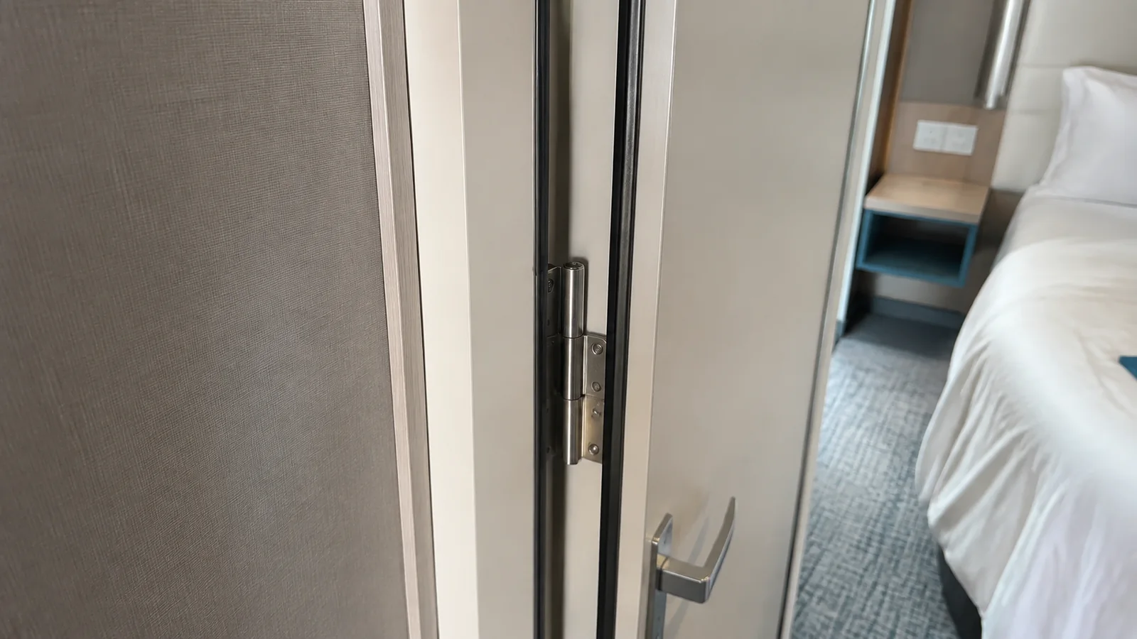 Partially open connecting door beside a cruise cabin bed