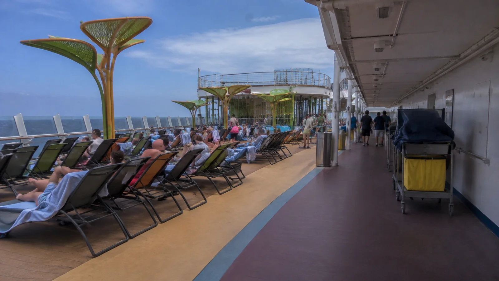 Passengers lounging beside a colorful walking track on a cruise ship deck