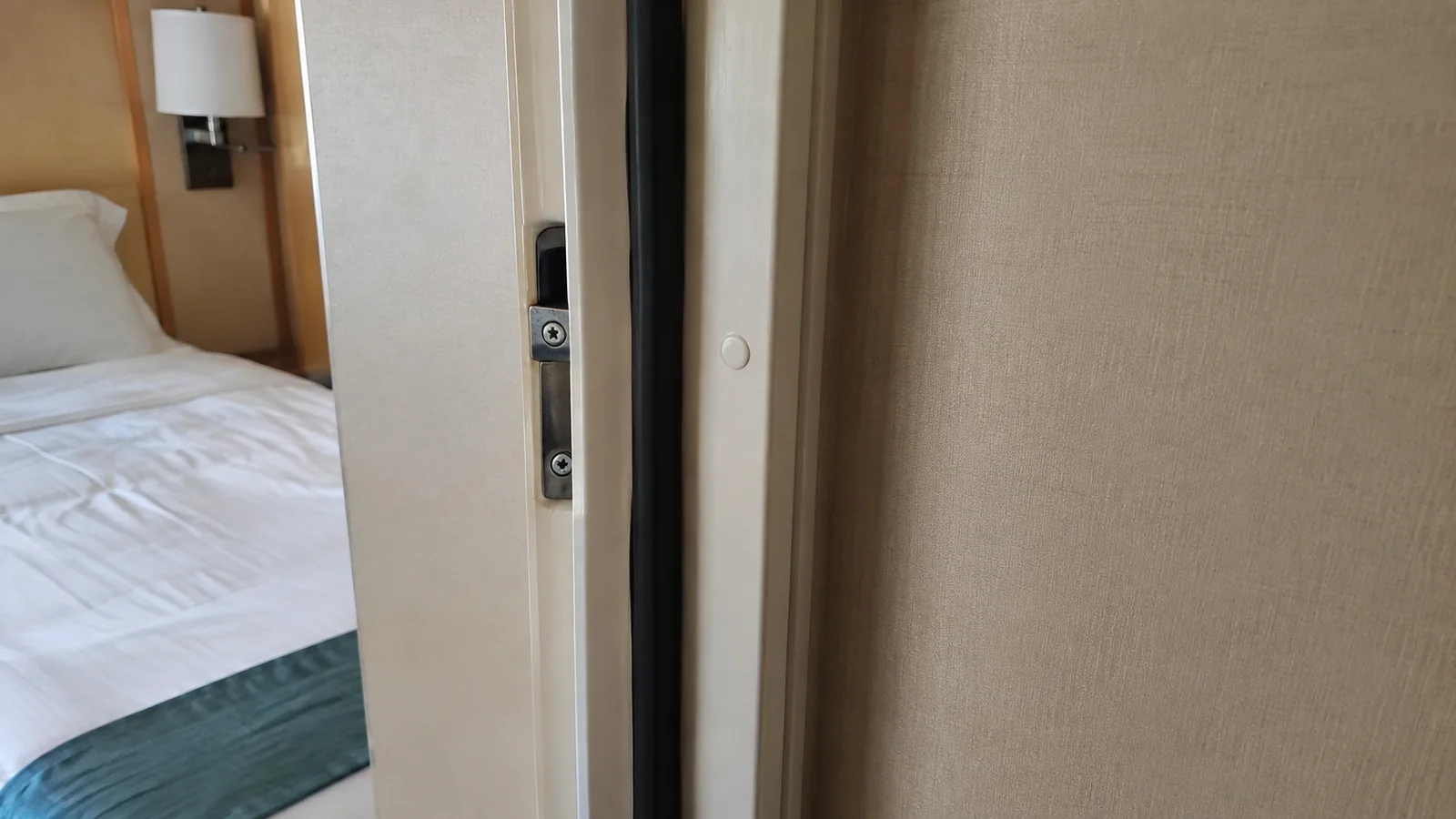 Partially open connecting door beside a cruise cabin bed
