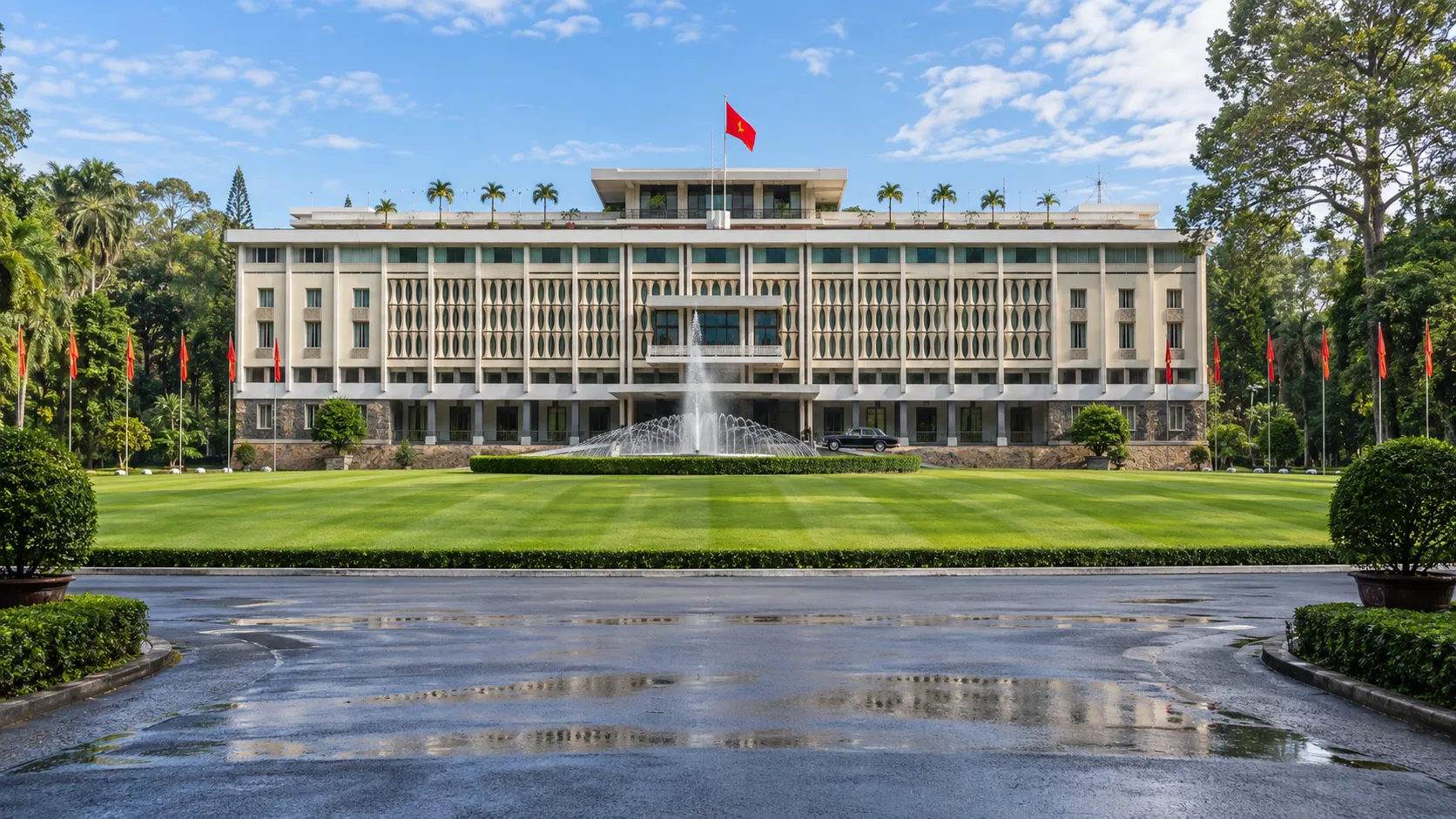 The modernist Independence Palace, fountain, and striped lawn beneath a clear sky in Ho Chi Minh City.