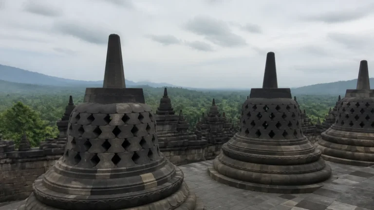 Bell-shaped stone stupas overlook a misty green landscape.