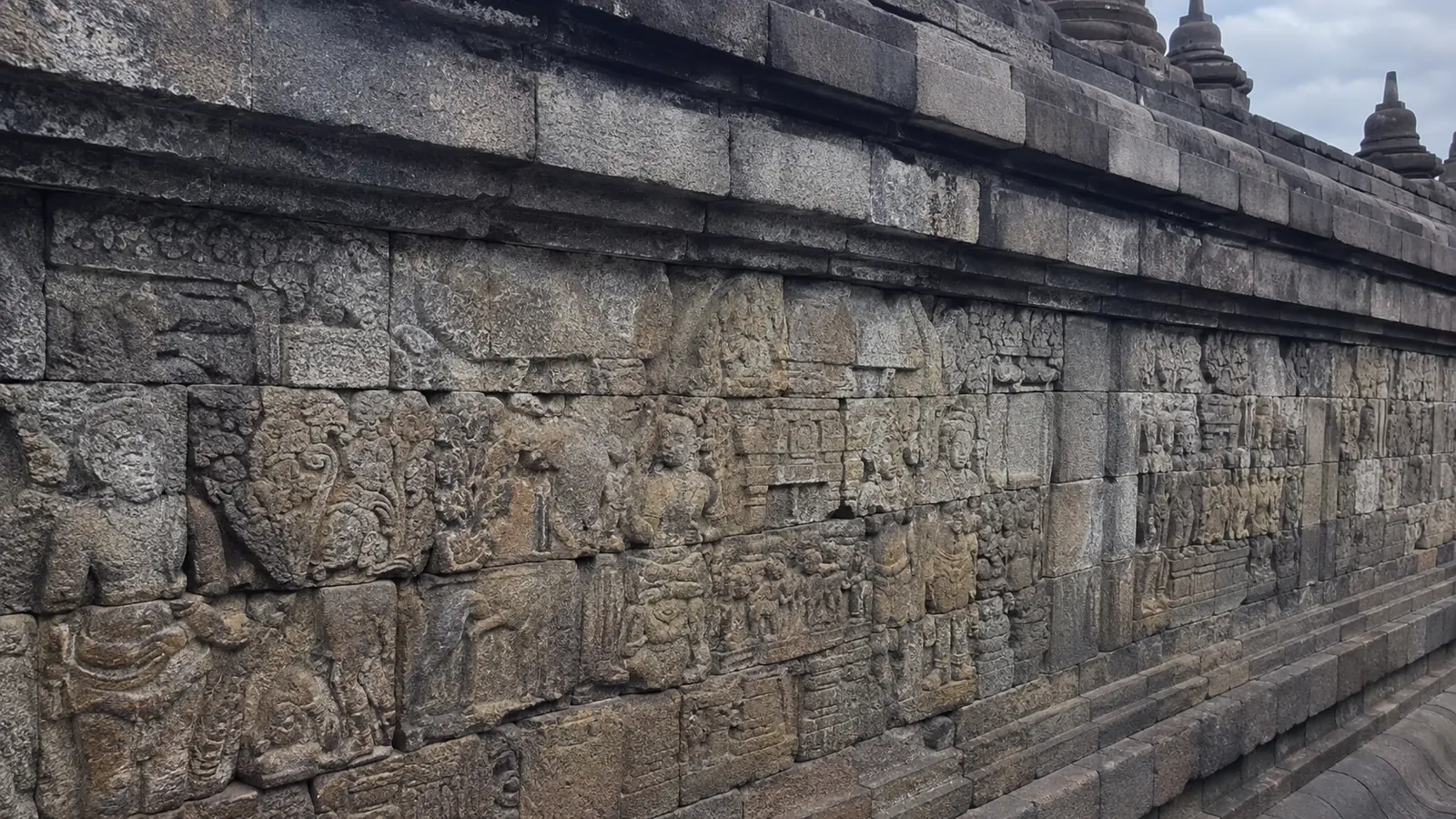Detailed carved reliefs cover the weathered wall of a stone temple.