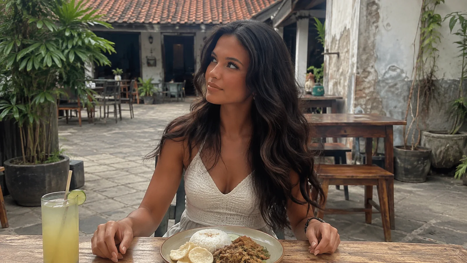 Woman seated with a drink in an open-air courtyard cafe.
