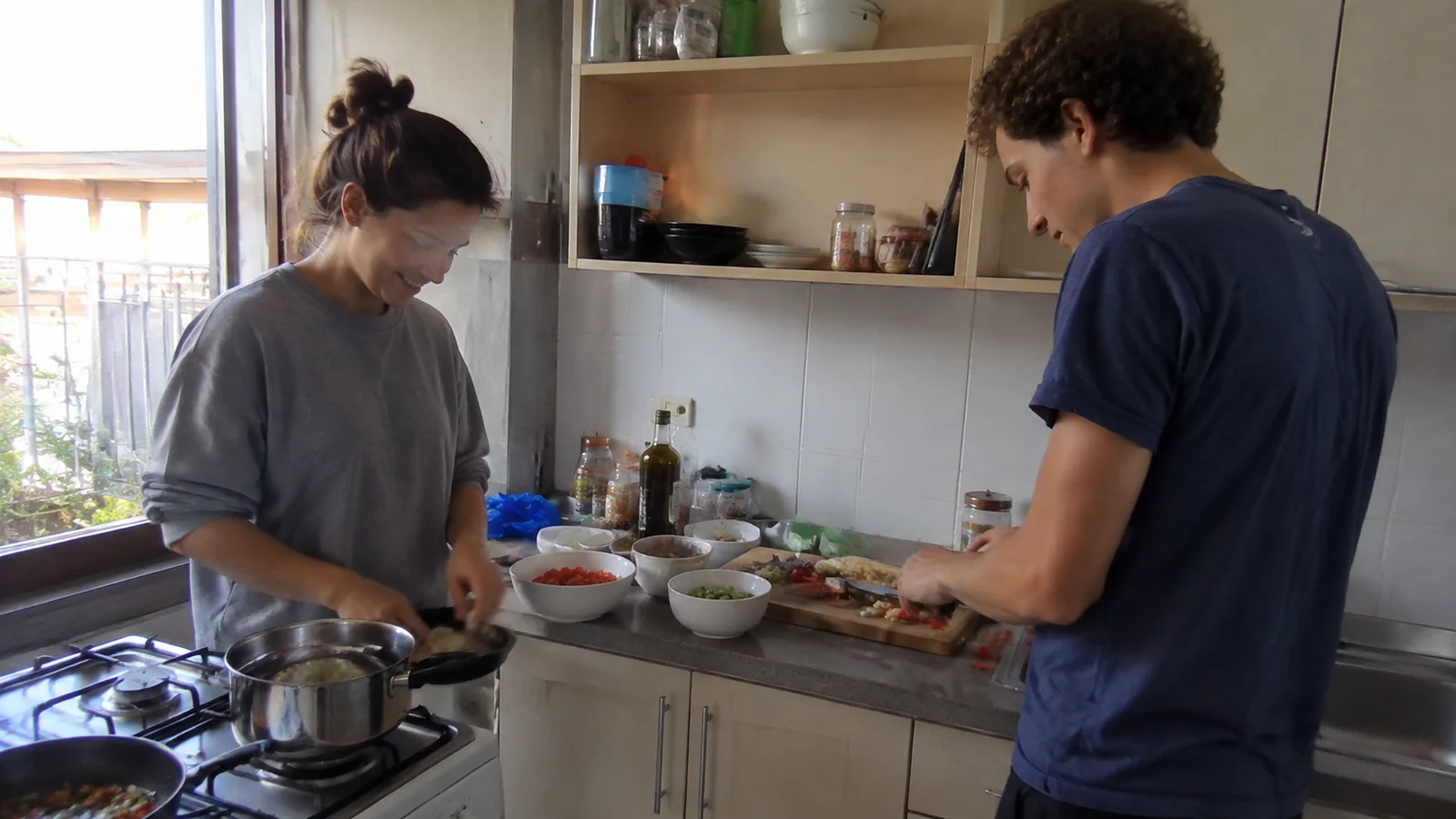 Two people preparing food together in a small kitchen.