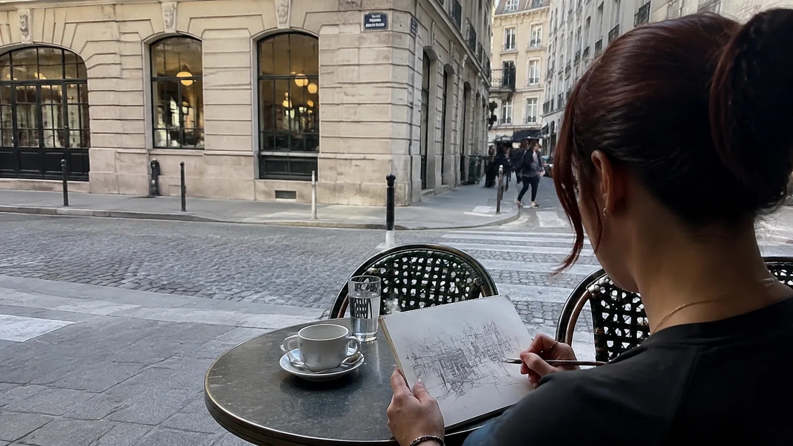 Woman reading a small notebook at a sidewalk cafe