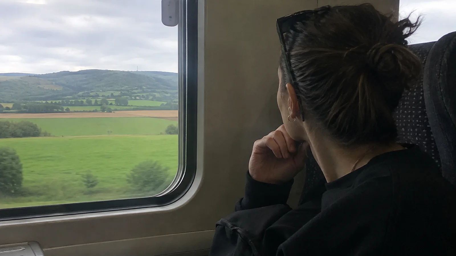 Woman watching green countryside through a train window