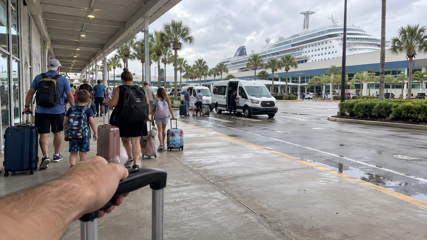 Families with luggage walking along the covered curb at a Jacksonville cruise terminal.