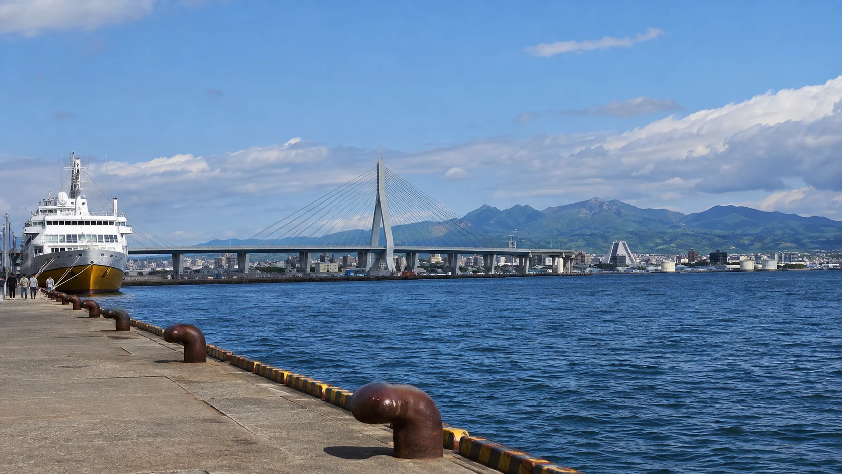 Aomori waterfront, bay bridge, and distant mountains.