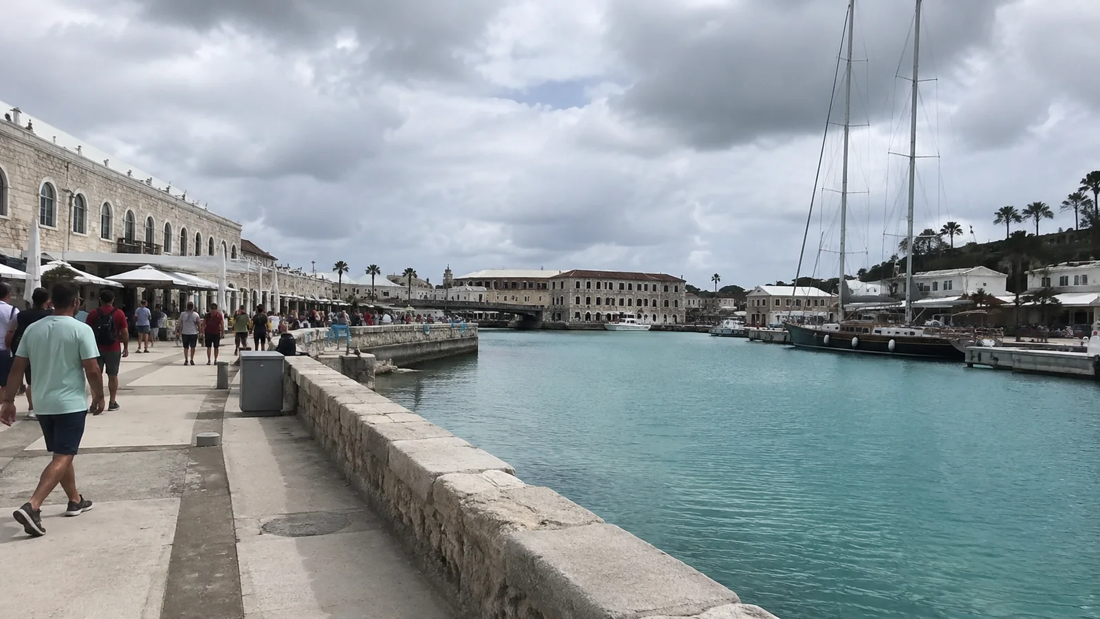 Stone waterfront walkway with historic buildings beside a harbor