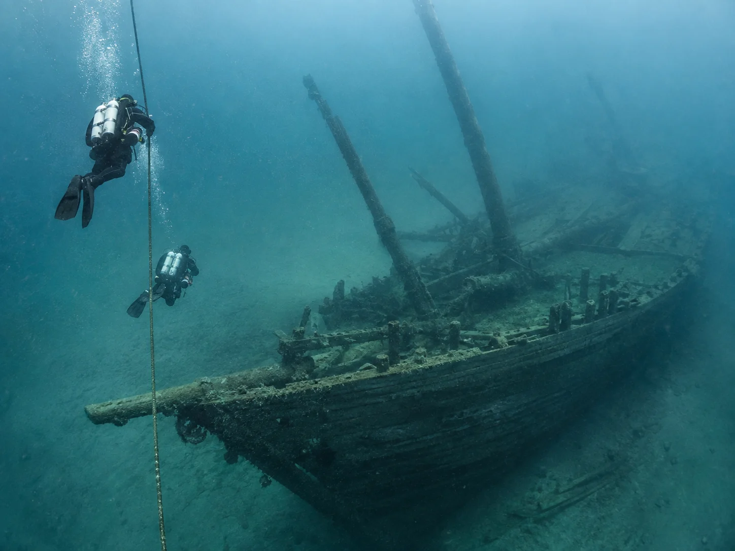 Two divers follow a mooring line toward the wooden schooner Lumberman in Lake Michigan.