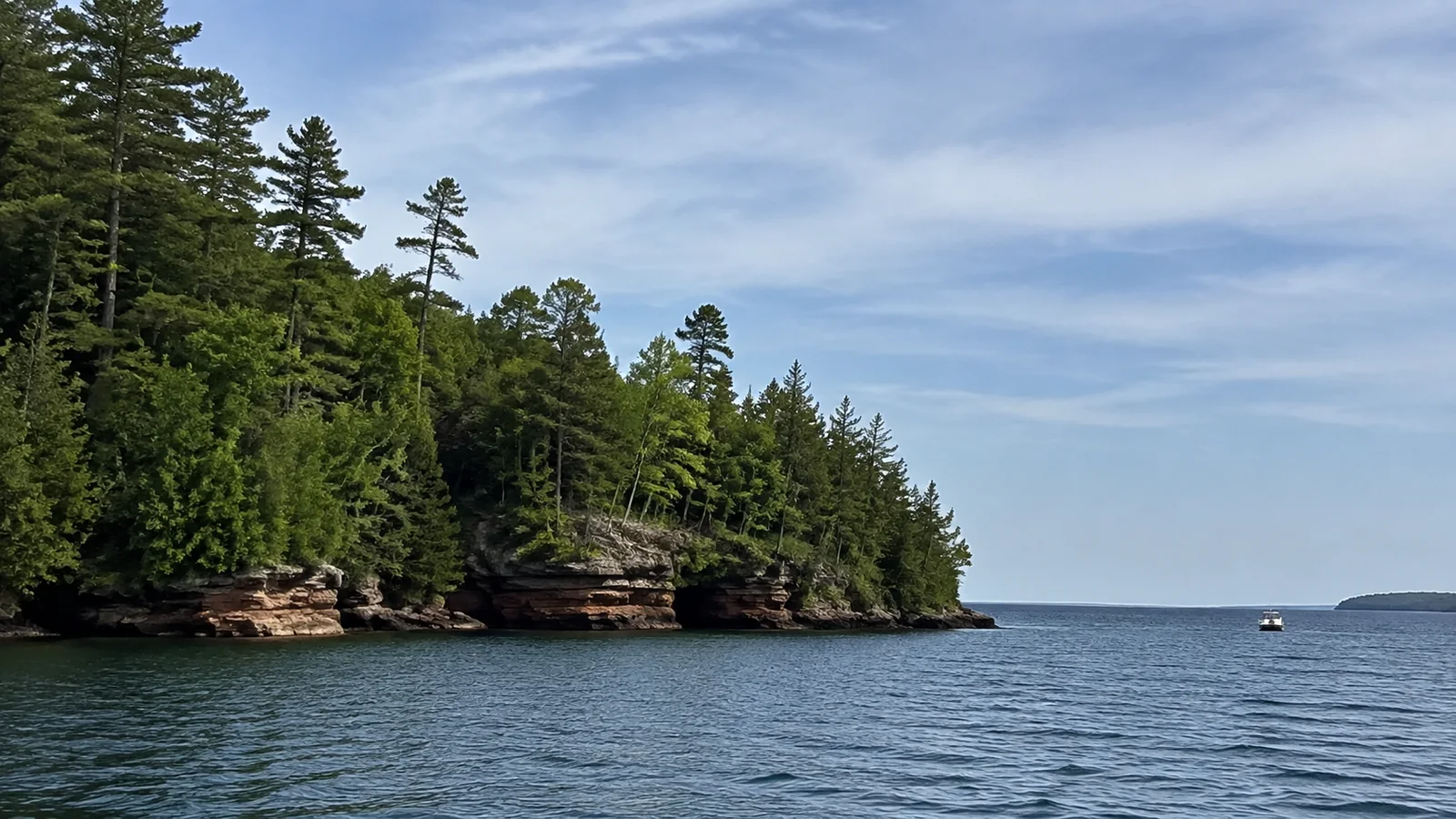 Tree-covered rocky point extends into a wide blue lake.
