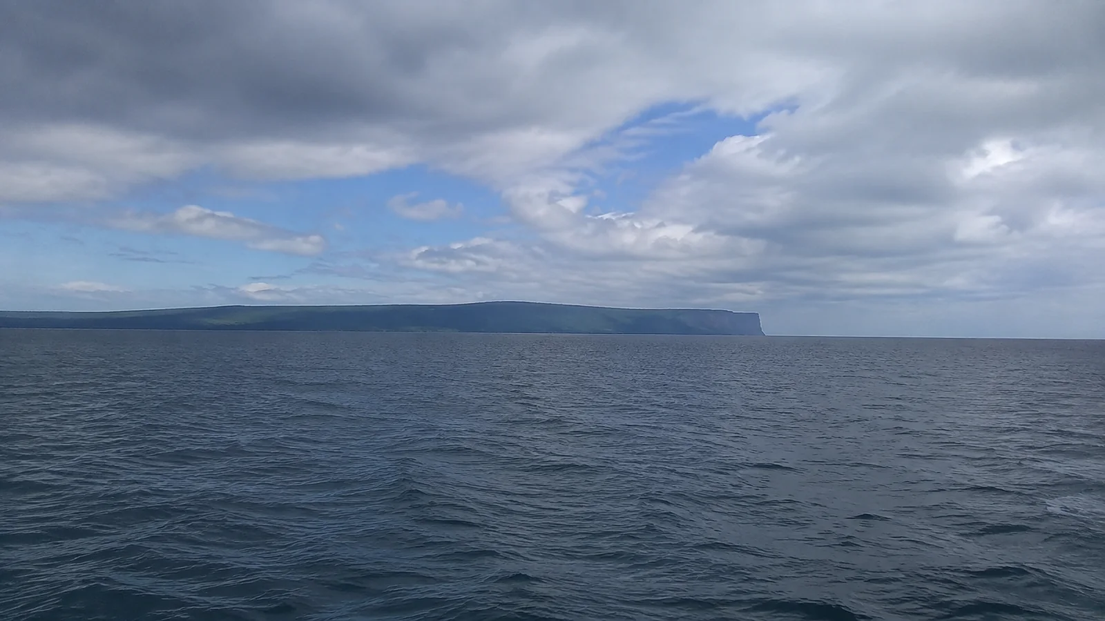 Distant flat-topped headland rises across a broad lake.