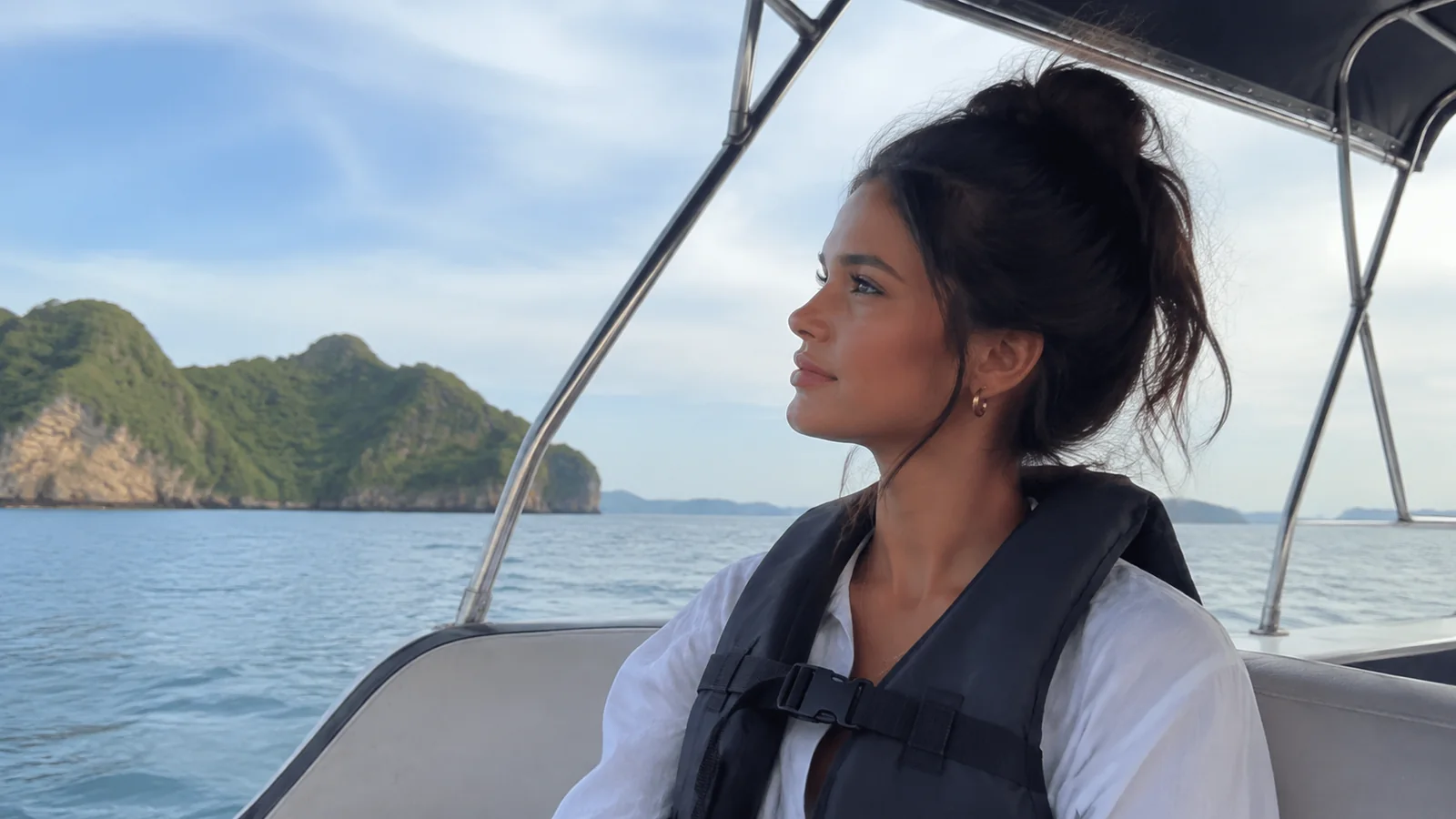 Woman wearing a life jacket aboard a boat near limestone islands.