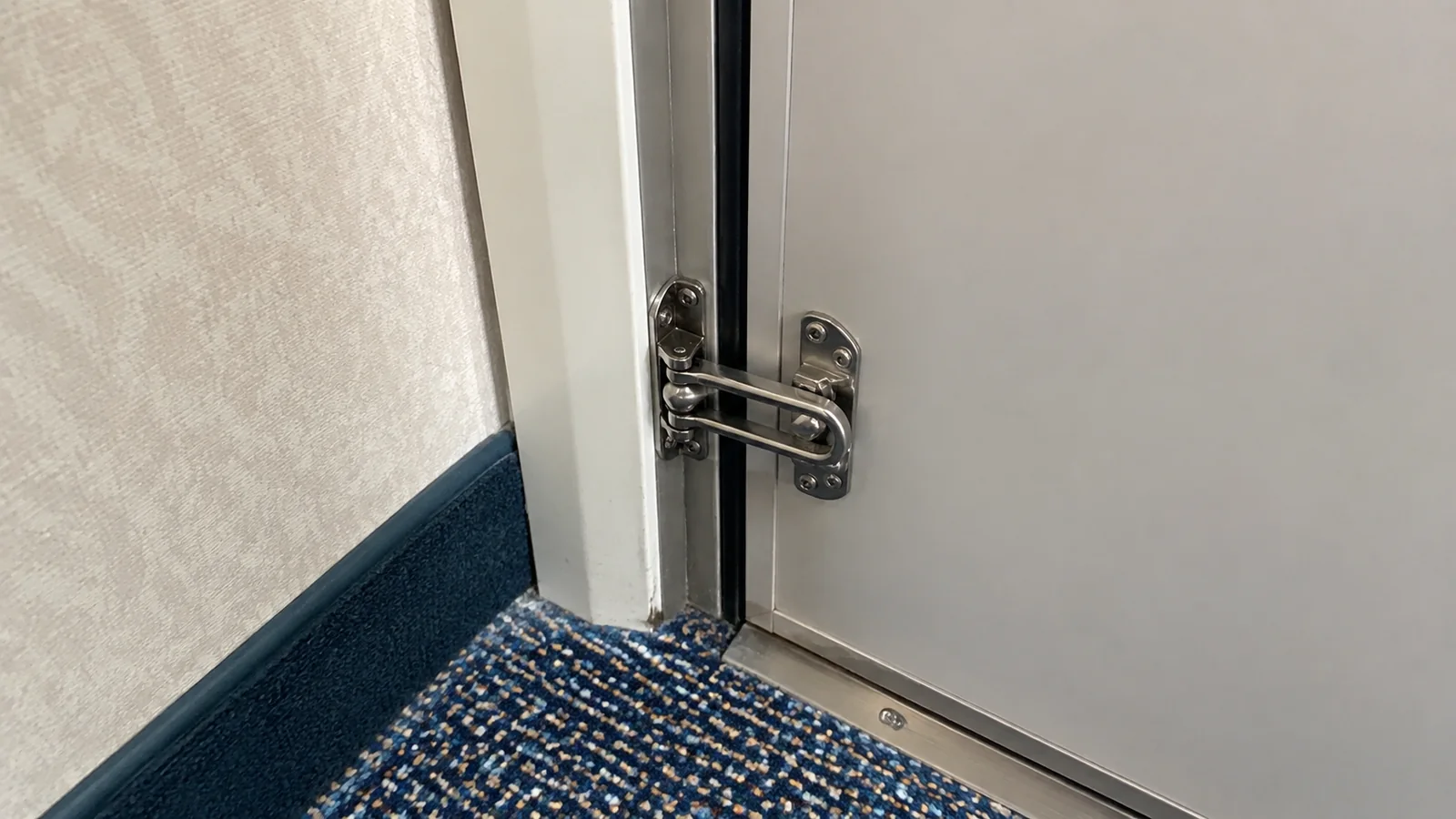 Close-up of a metal door latch near the cabin floor.