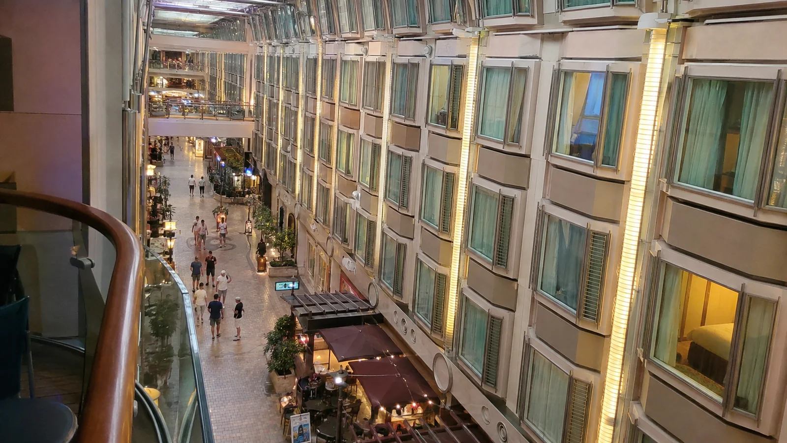 Interior ship promenade lined with shops and inward-facing cabin windows.