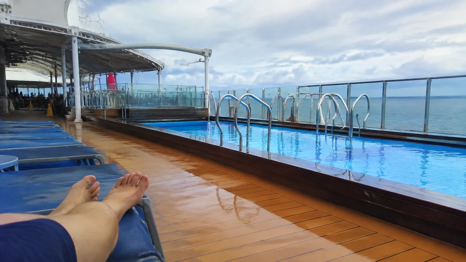 Passenger reclining beside a cruise ship pool overlooking the ocean