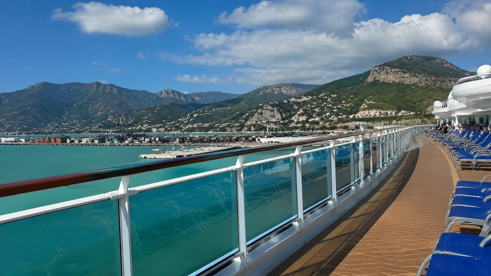 Cruise ship pool deck overlooking a mountainous harbor