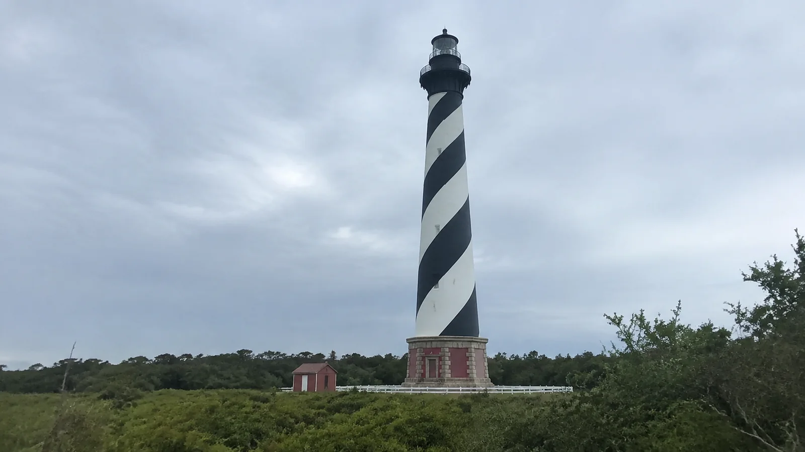 Black-and-white spiral-striped lighthouse beneath an overcast sky