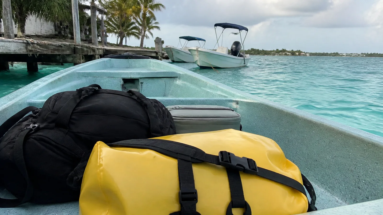 Backpack and yellow dry bag secured inside a small open boat.