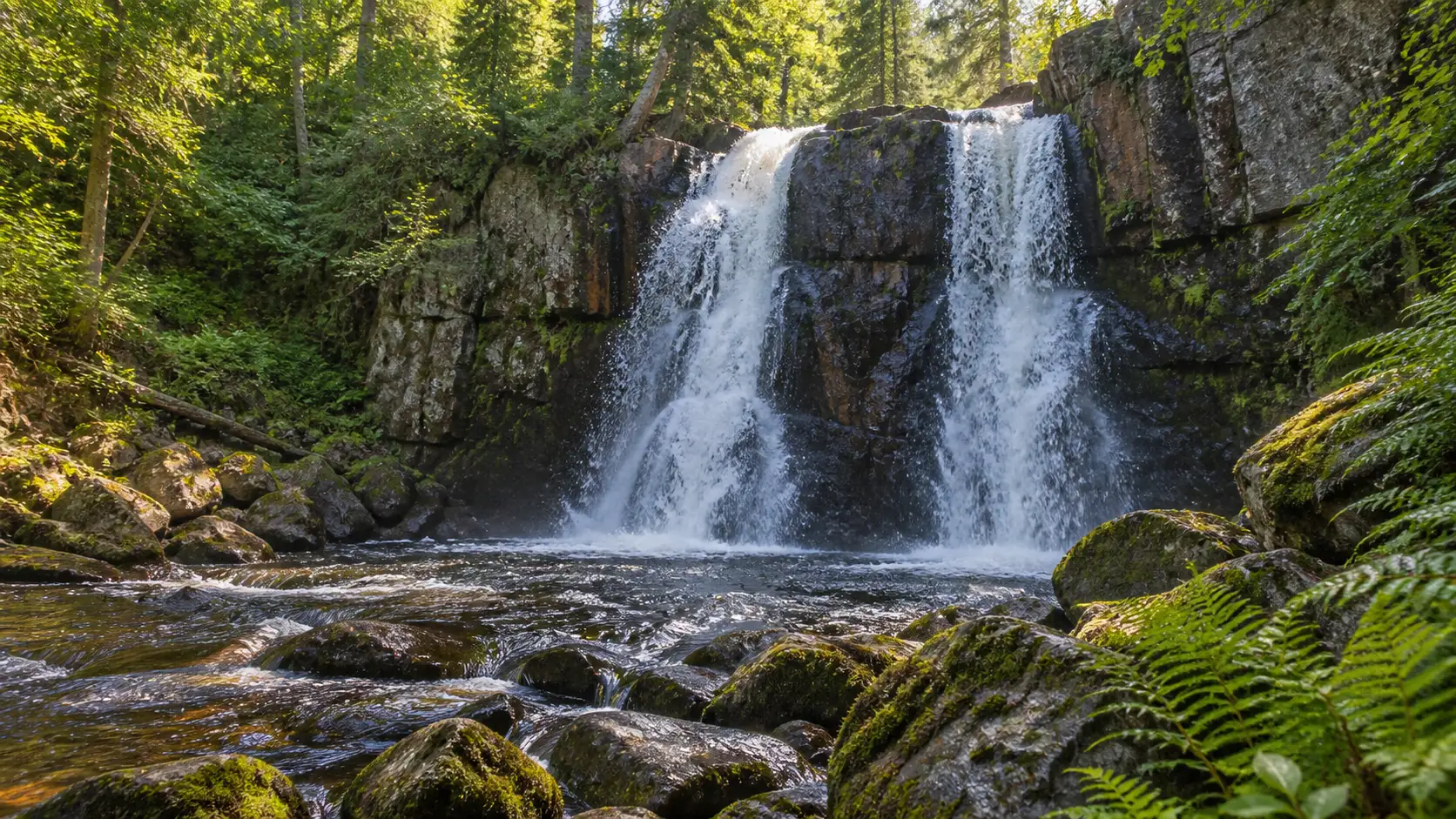 Little Manitou Falls splitting into two channels over a dark rock ledge in Pattison State Park.