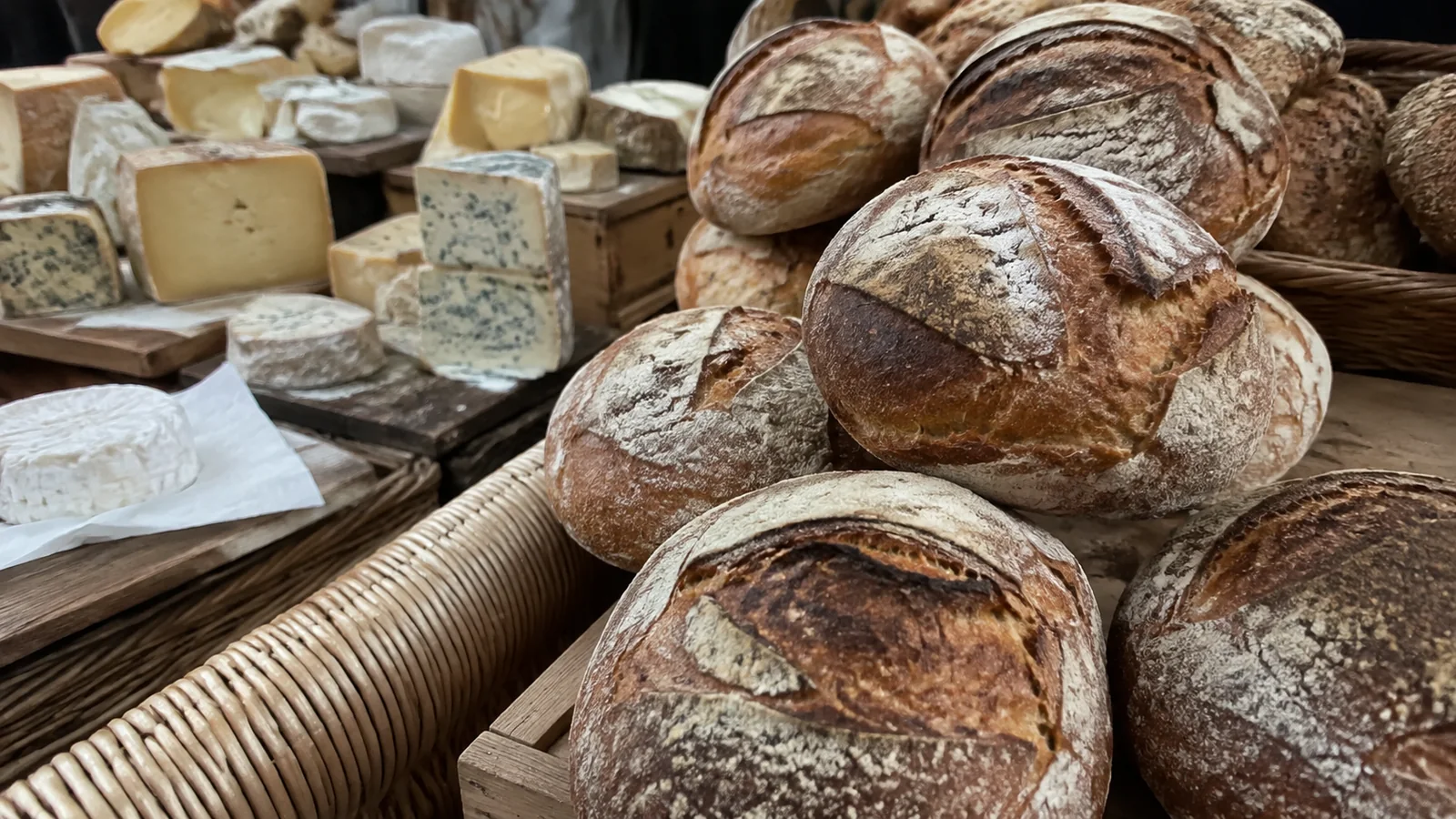 Round rustic loaves and cheeses displayed on a market counter.