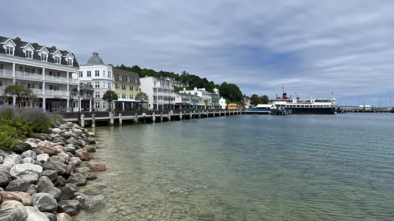 White waterfront buildings beside a sheltered harbor and passenger ferry.