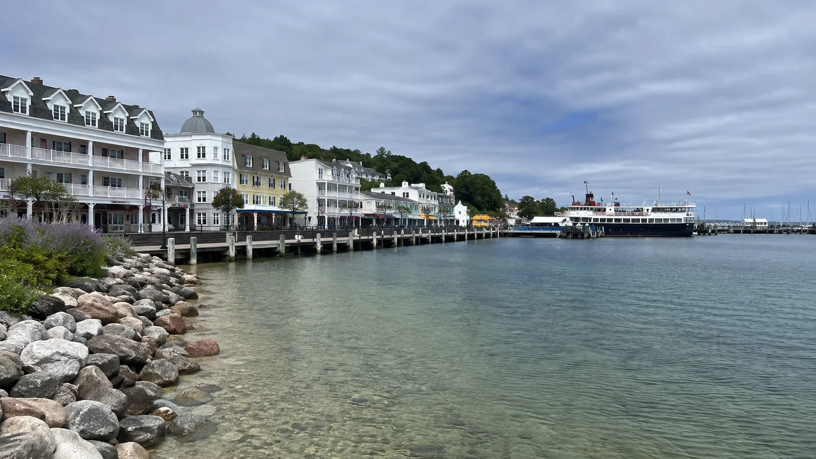 White waterfront buildings beside a sheltered harbor and passenger ferry.