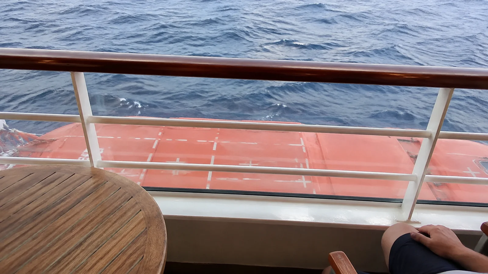 View from a balcony table down toward an orange lifeboat.