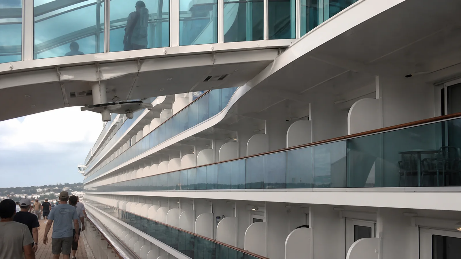 Glass walkway projecting above rows of cruise cabin balconies.
